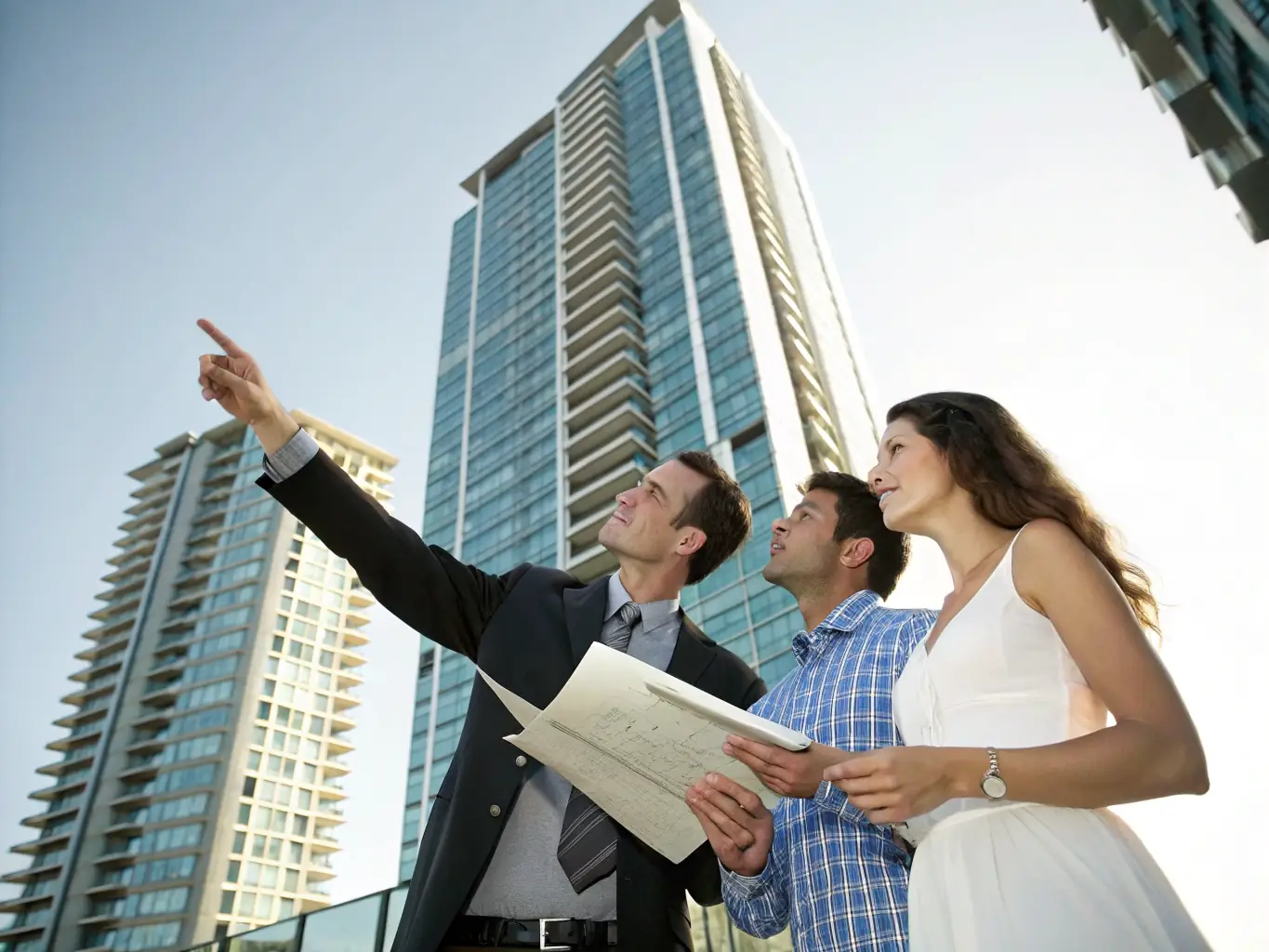 A modern commercial building and residential apartment complex with a real estate agent showing property plans, representing Atika Works' real estate services.